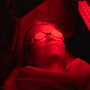 Client experiencing a soothing red light facial treatment for relaxation.